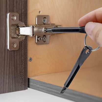 Hand using a mini keychain screwdriver to tighten a cabinet door hinge